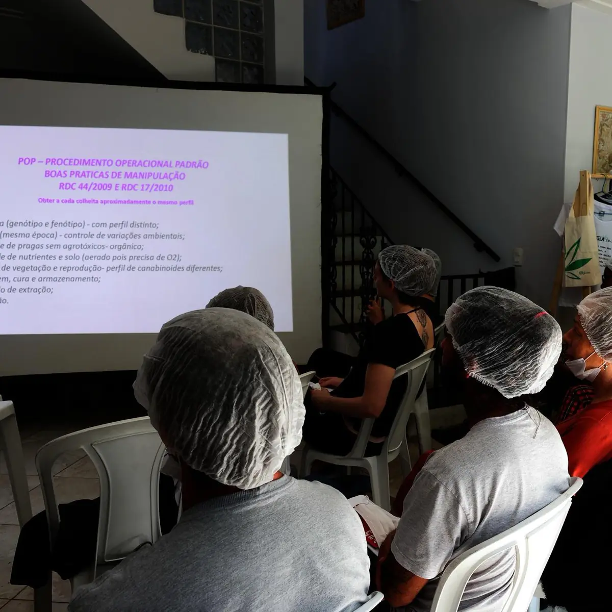 Alunos de touca assistindo a uma aula sobre boas práticas de manipulação